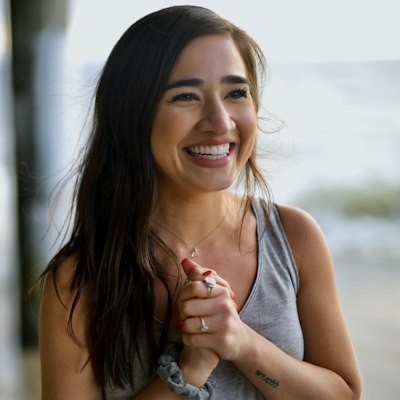 A smiling woman with long dark hair in soft natural light